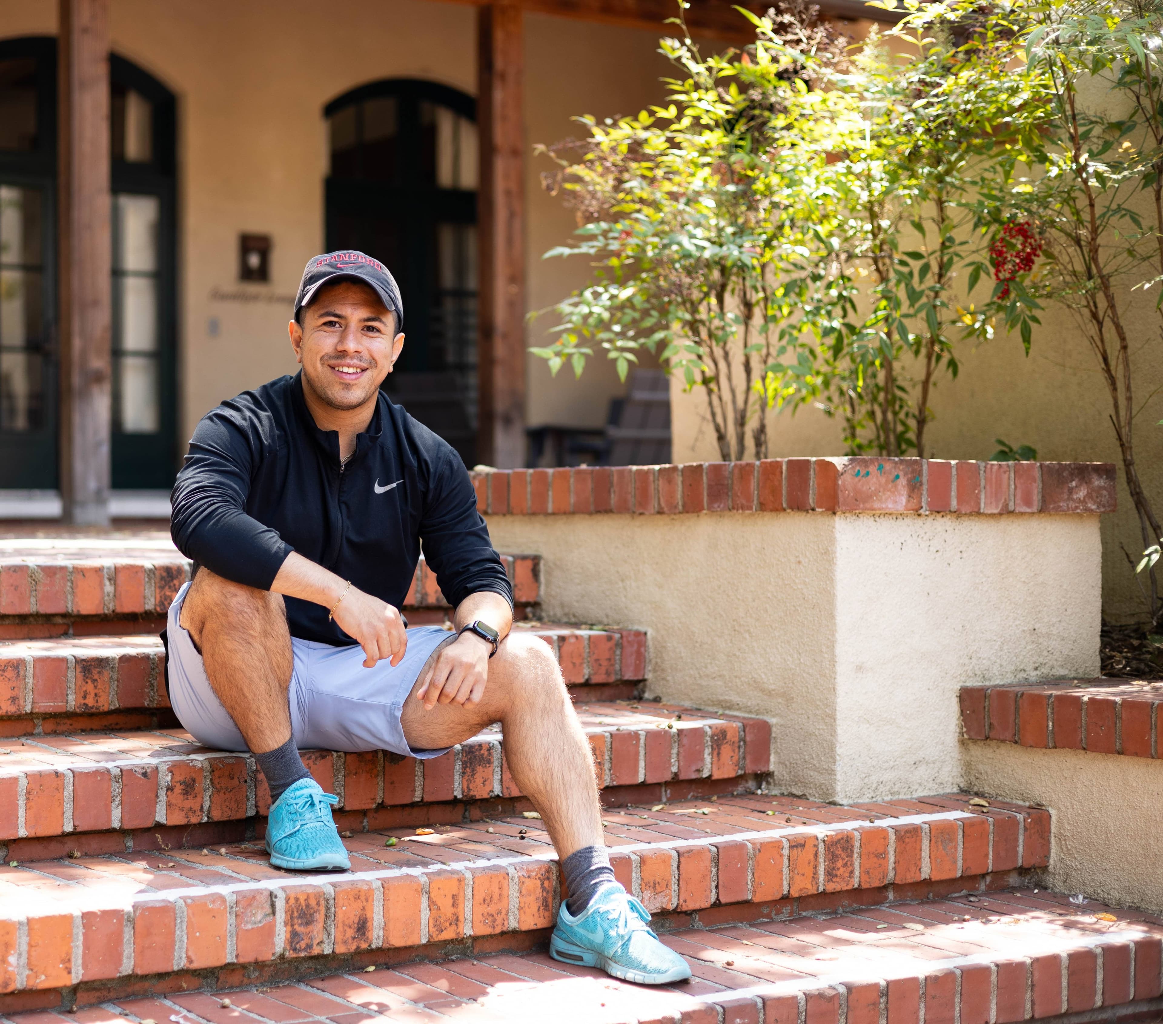 A student sits on the steps outside smiling. (Photo credits to Cayden Gu/Ethography for Stanford Summer Session)